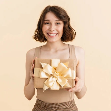 Smiling woman holding a wrapped gift box representing personalized gifts for yourself collection