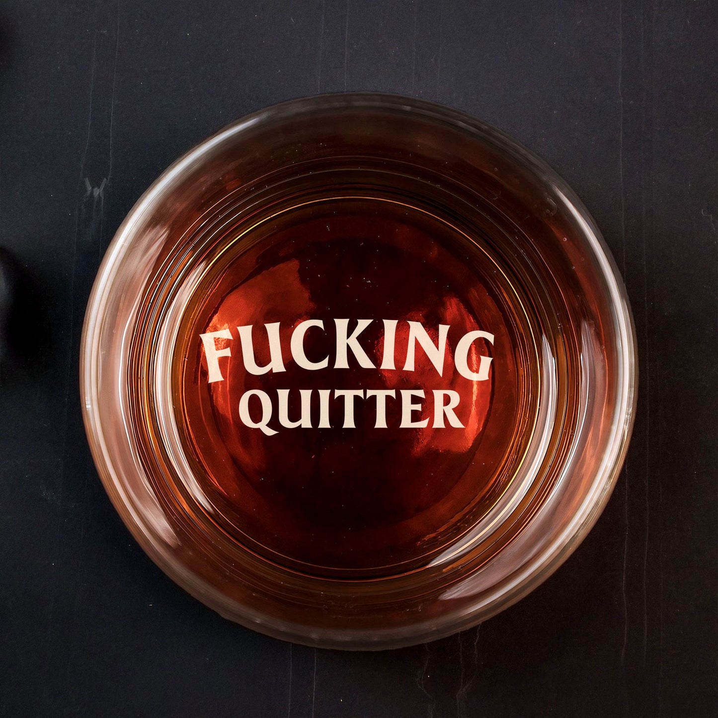 Top view of 365Gifty Personalized Whiskey Glass with amber whiskey and bold engraved wording FUCKING QUITTER
