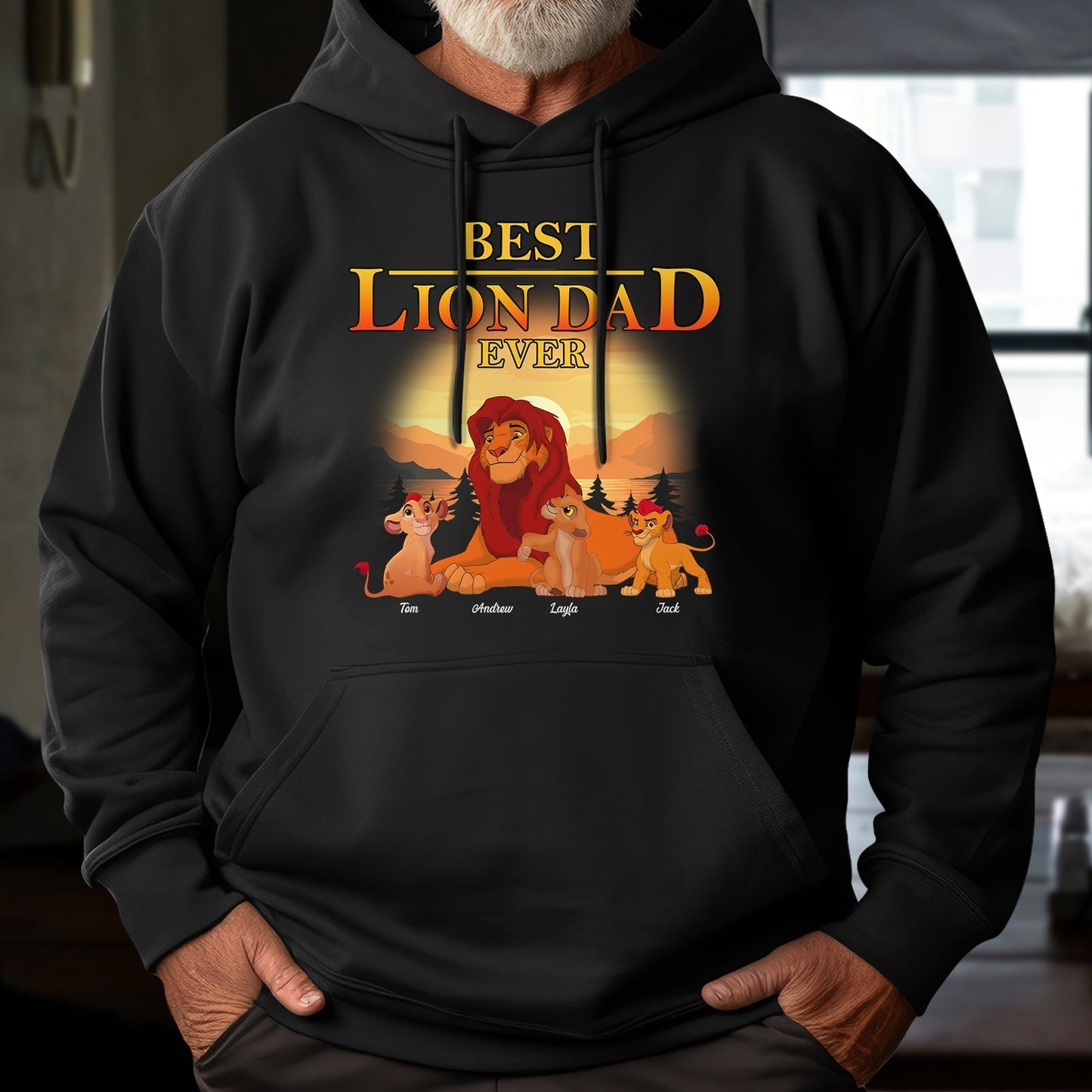 Black hoodie featuring the best lion dad ever t-shirt design with cartoon lion family and sunset background