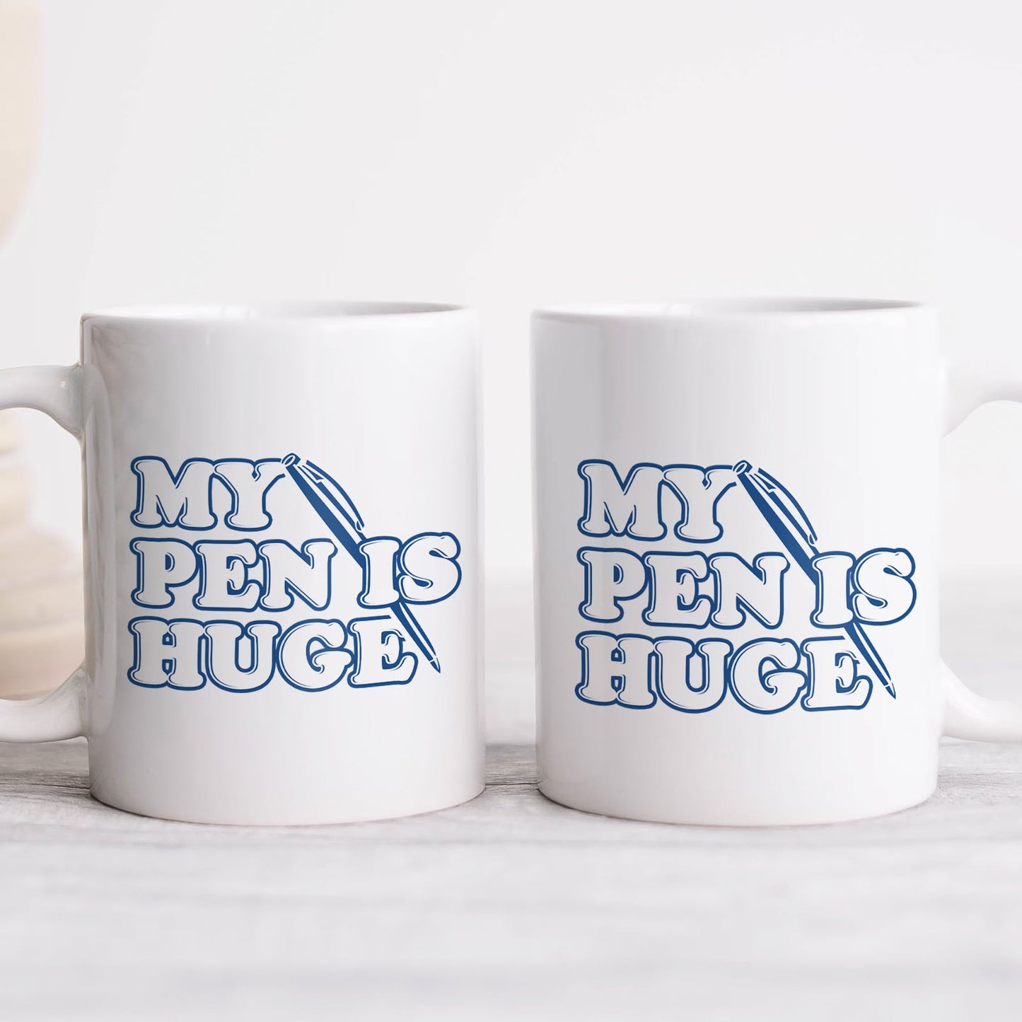 Pair of white ceramic my pen is huge coffee mug with blue retro text and pen illustration