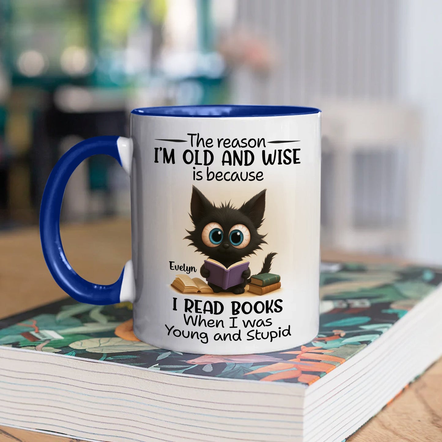 funny personalized accent mug for bookworms featuring a cute black kitten reading a book on white mug with blue handle
