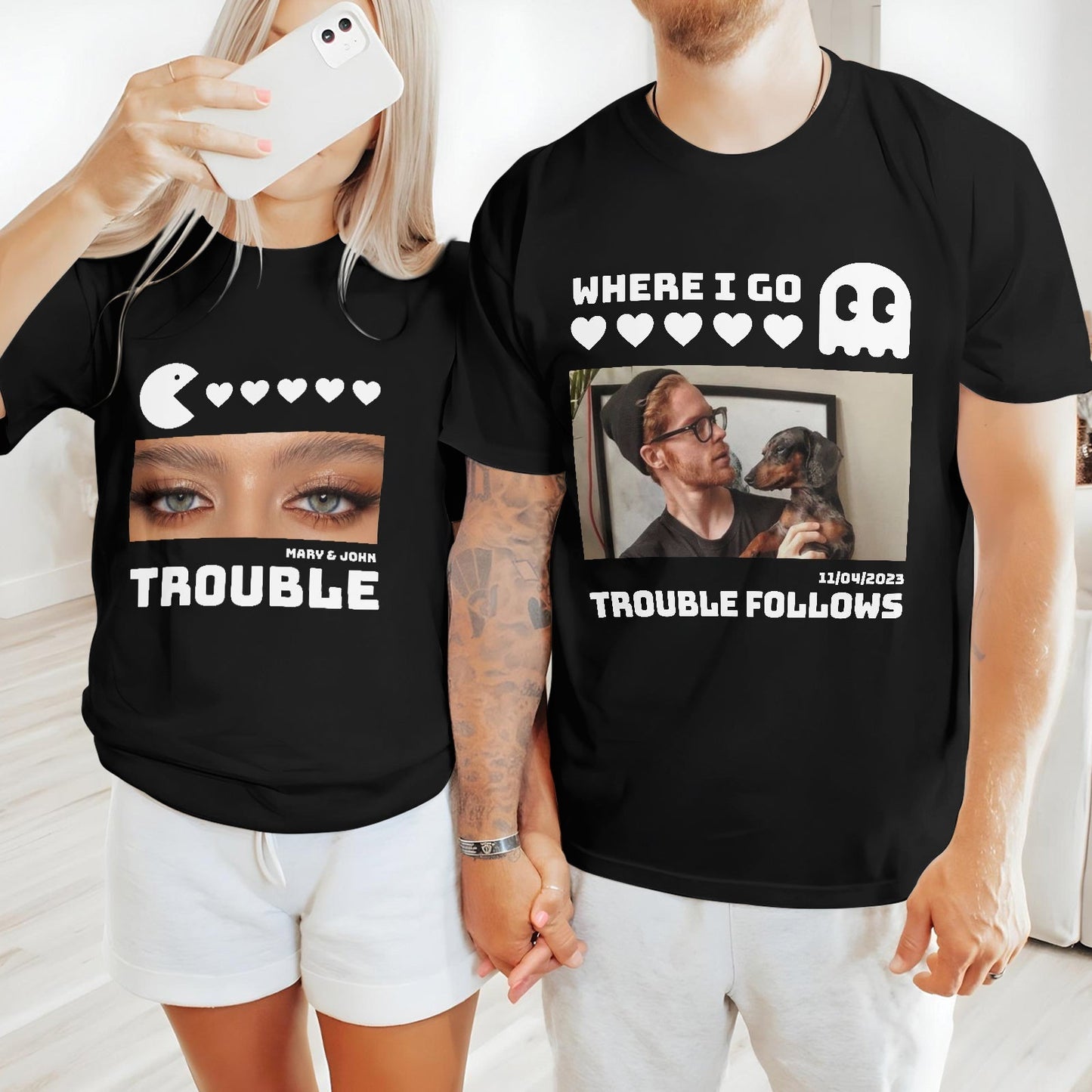 Couple wearing black matching trouble shirts for couples holding hands, featuring playful graphic designs