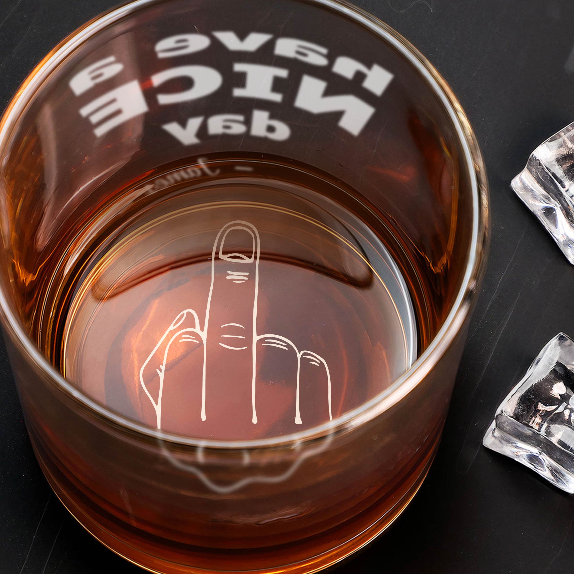 Personalized Whiskey Glass with engraved middle finger at the bottom filled with amber whiskey and ice