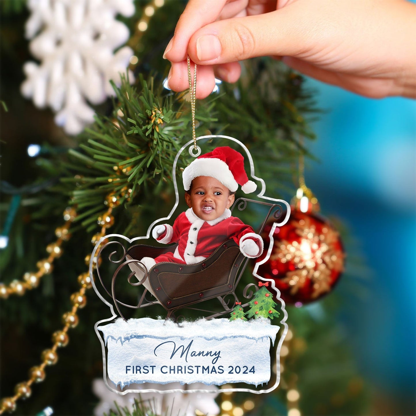 Custom first Christmas acrylic ornament featuring a baby in Santa outfit sitting in a sleigh with name Manny and 2024 date