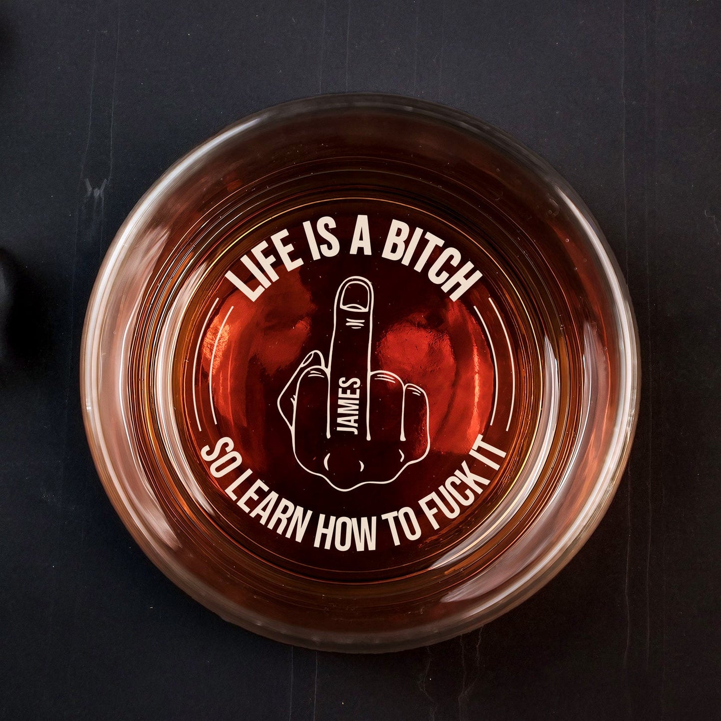 365Gifty Personalized Whiskey Glass top view with amber whiskey and etched middle finger design reading Life Is A Bitch