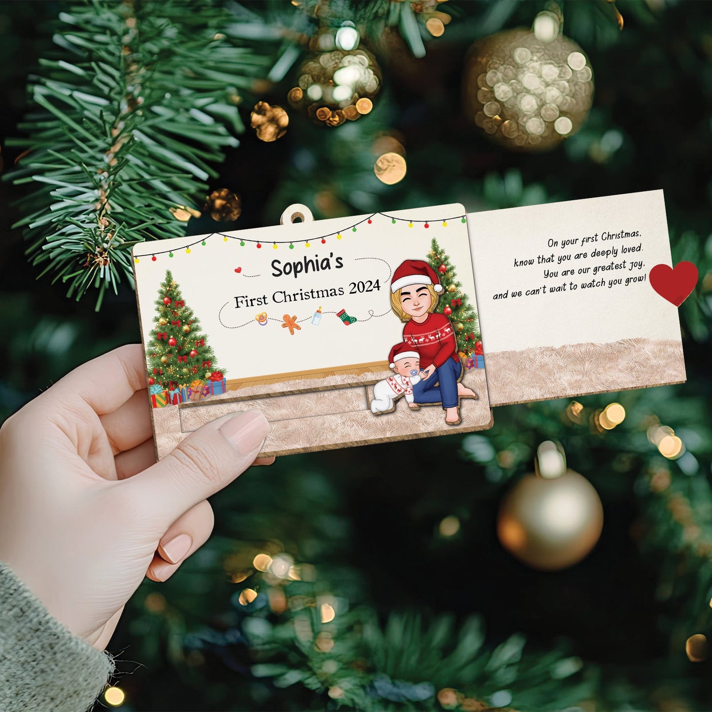 Hand holding a custom wooden Christmas slider card personalized for Sophia's first Christmas 2024 with festive decorations