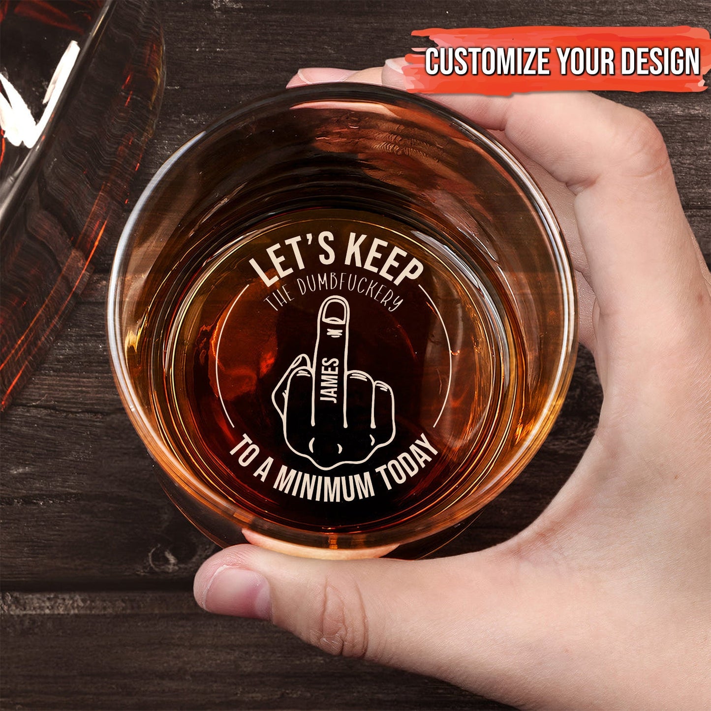 Hand holding Personalized Whiskey Glass top view with engraved middle finger design and customizable name and humorous slogan