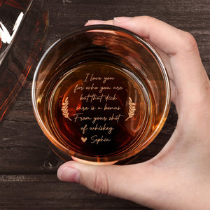 Personalized Whiskey Glass top view held in hand with amber whiskey and cheeky engraved love message at bottom on wooden table