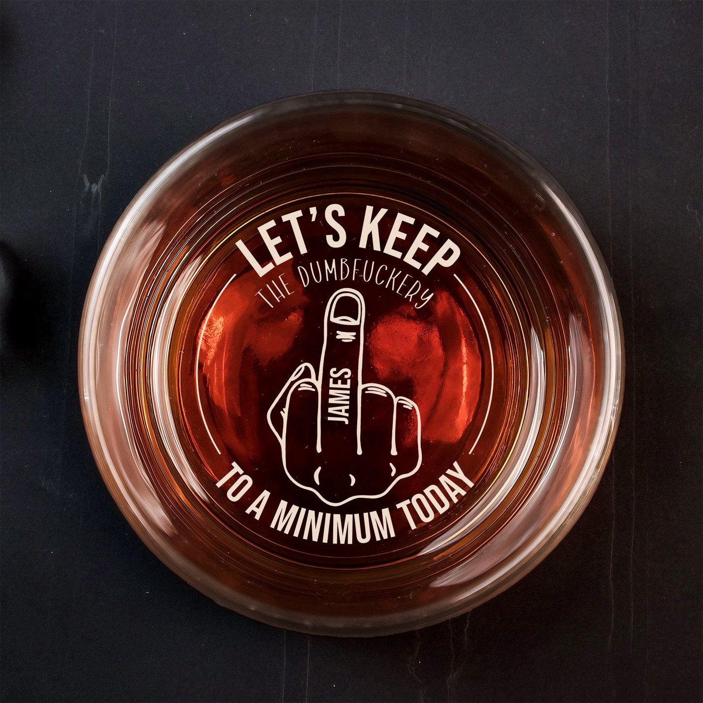 Top view Personalized Whiskey Glass filled with amber whiskey and white cheeky middle finger engraving with name James