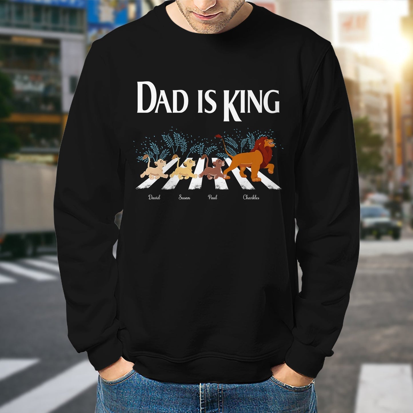 Black dad lion king shirt with cartoon lions crossing a street and text dad is king