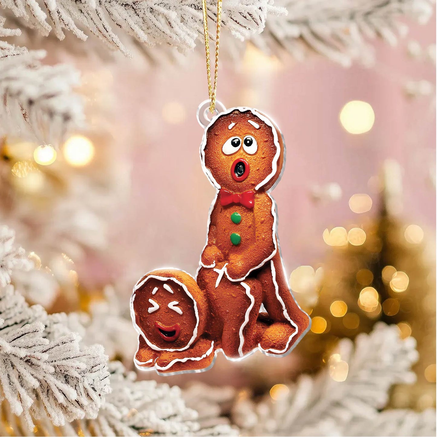 Funny Christmas ornament featuring two animated gingerbread figures with expressive faces hanging on a snowy tree branch