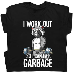 Black t-shirt featuring humorous workout apparel with a muscular raccoon lifting weights and text I work out so I can eat garbage