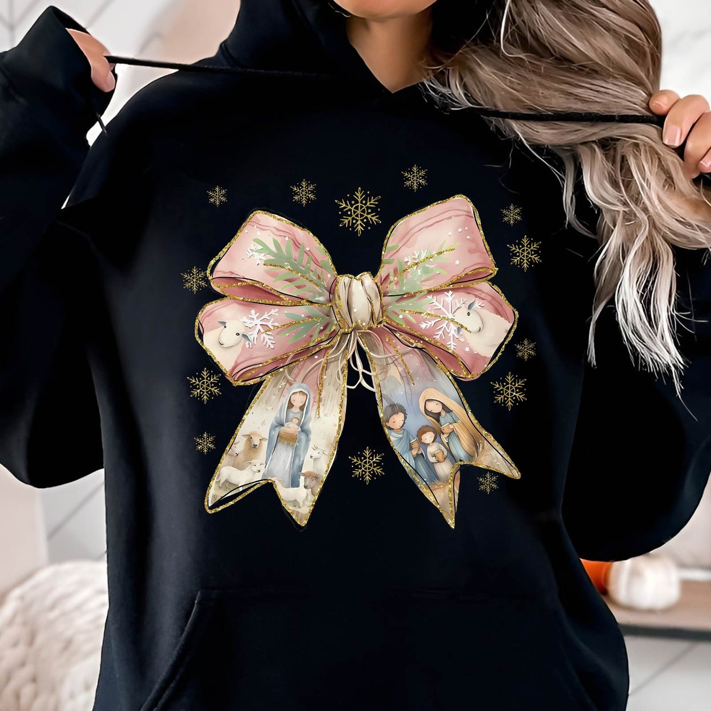 Black hoodie featuring Jesus Christmas bow shirt design with nativity scene and gold snowflakes