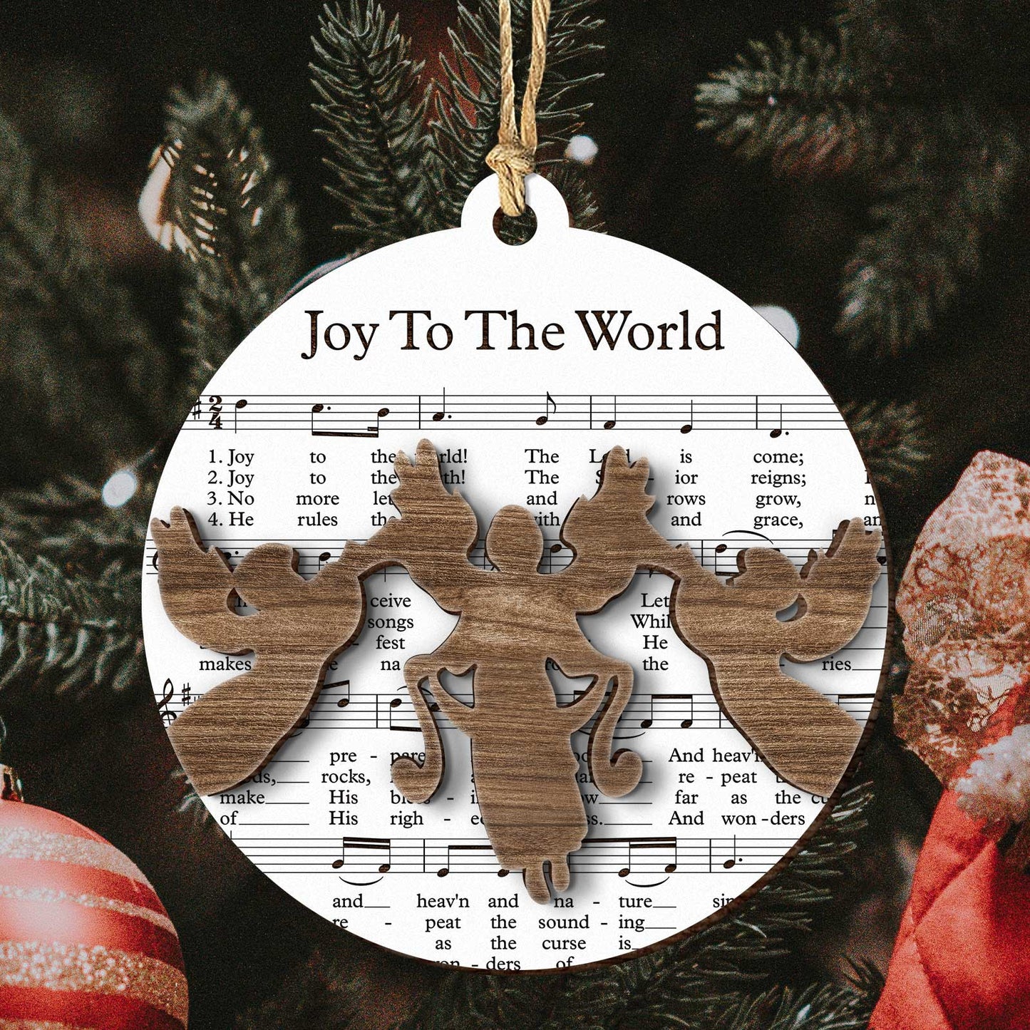 Music sheet nativity ornament featuring Joy To The World sheet music with wooden angel cutouts hanging on Christmas tree
