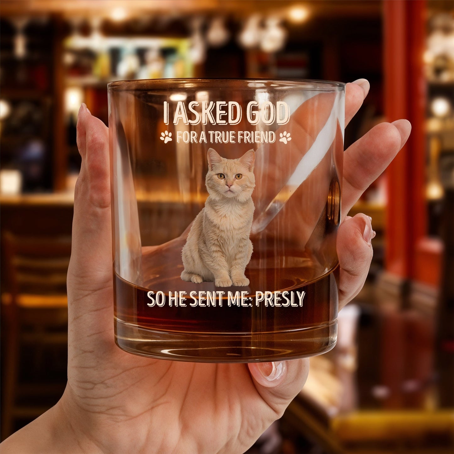 Hand holding personalized pet memorial whiskey glass etched with a cat portrait and memorial text