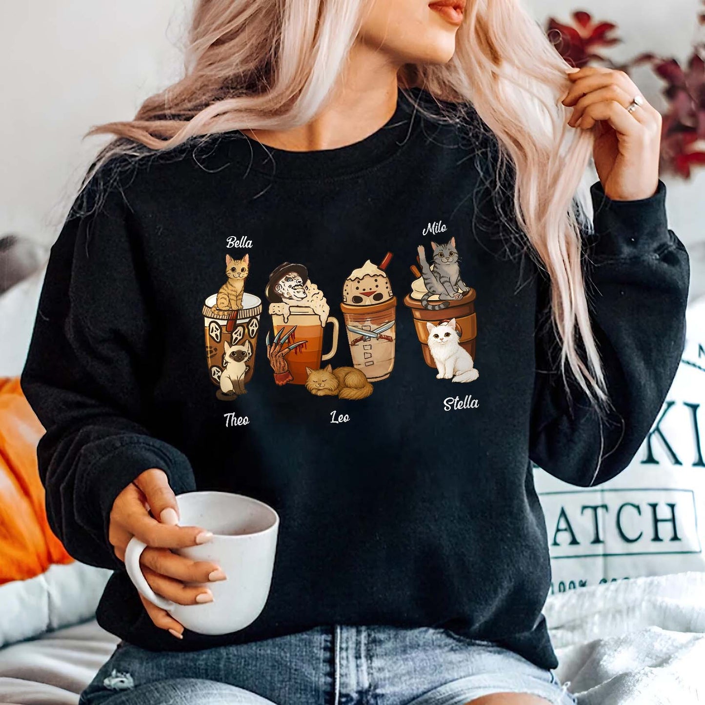Black personalized halloween cat shirt featuring cute cats with Halloween-themed drinks worn by a woman holding a white mug