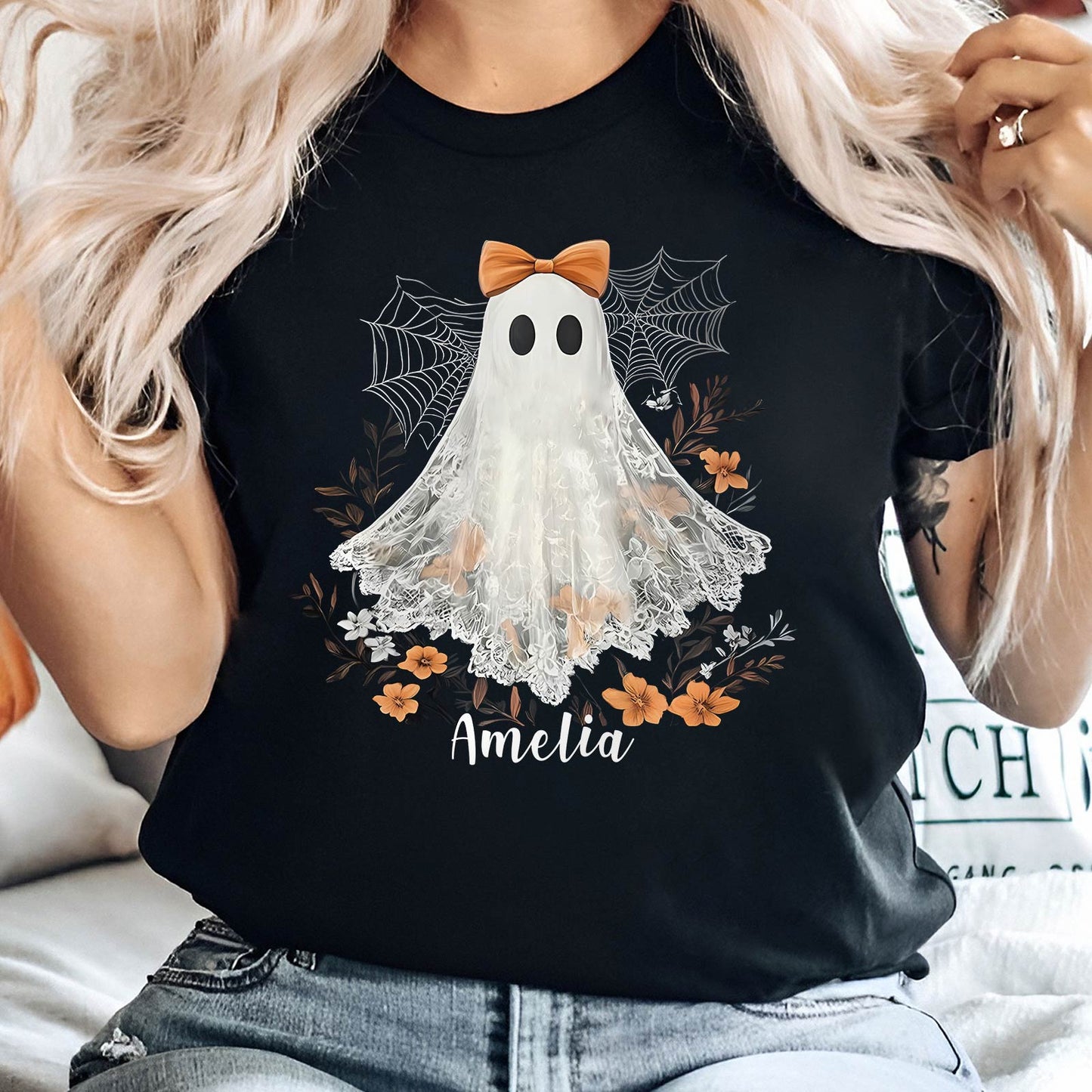 Black personalized Halloween shirt with white ghost, orange bow, spider webs, flowers, and name Amelia