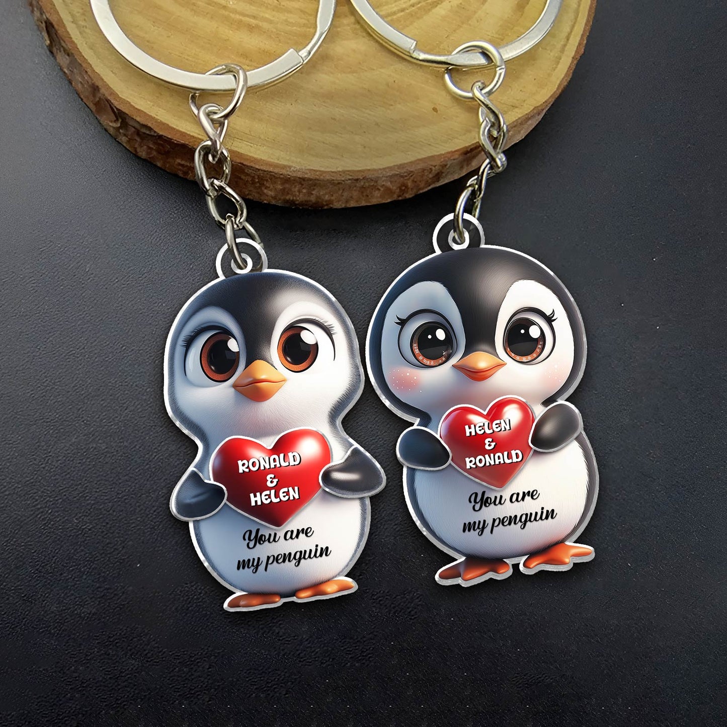 Personalized penguin couple keychain featuring smiling penguins holding a heart with custom names