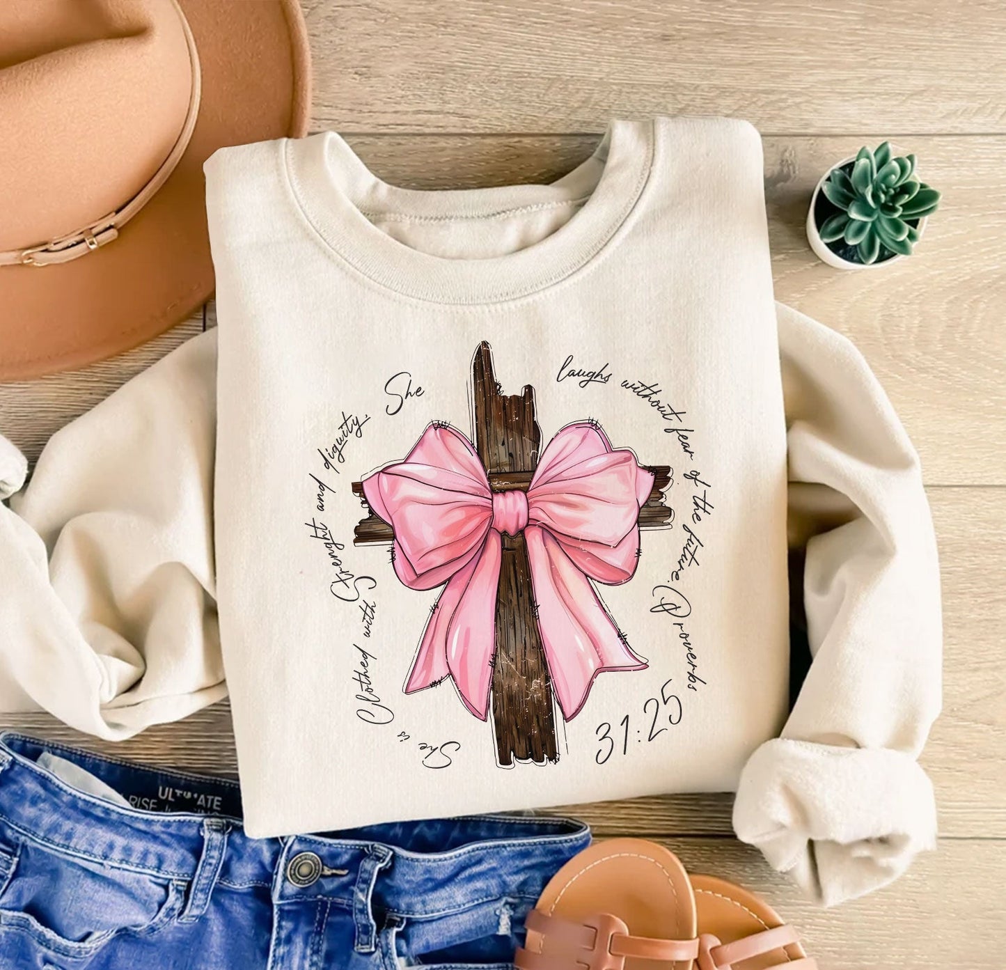 Personalized pink bow t-shirt with cross design and inspirational text folded on wooden surface