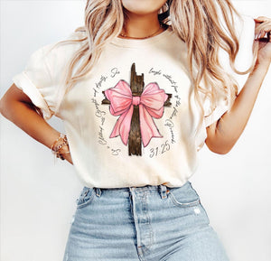 Woman wearing a personalized pink bow t-shirt with a large pink bow and cross design paired with light blue jeans