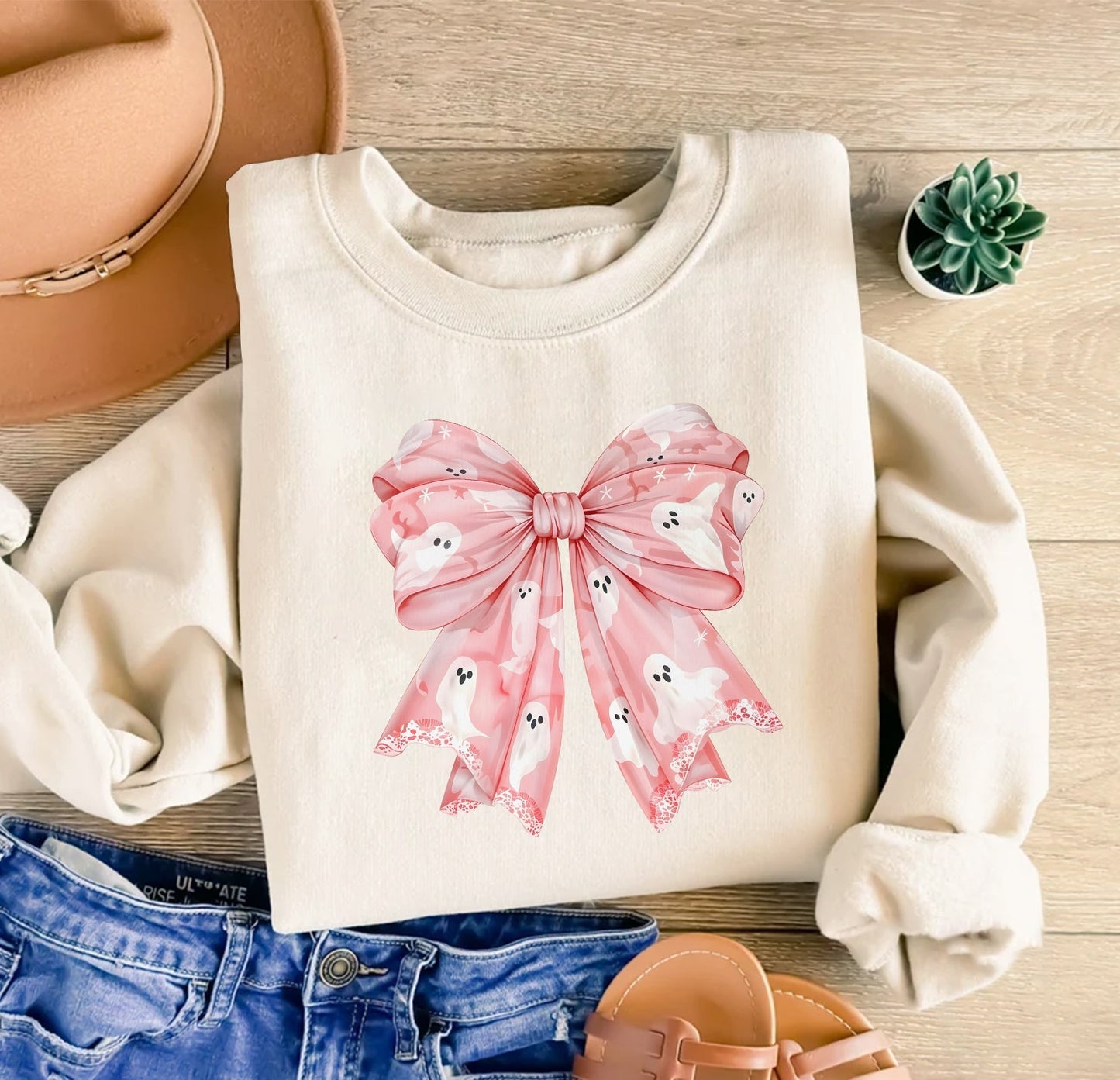 White sweatshirt with a personalized pink Halloween shirt design featuring a large pink bow with ghost prints