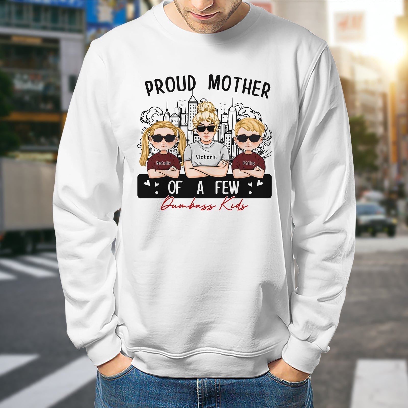 White sweatshirt featuring graphic design that reads Proud Mom of a Few Dumbass Kids with fun character illustrations