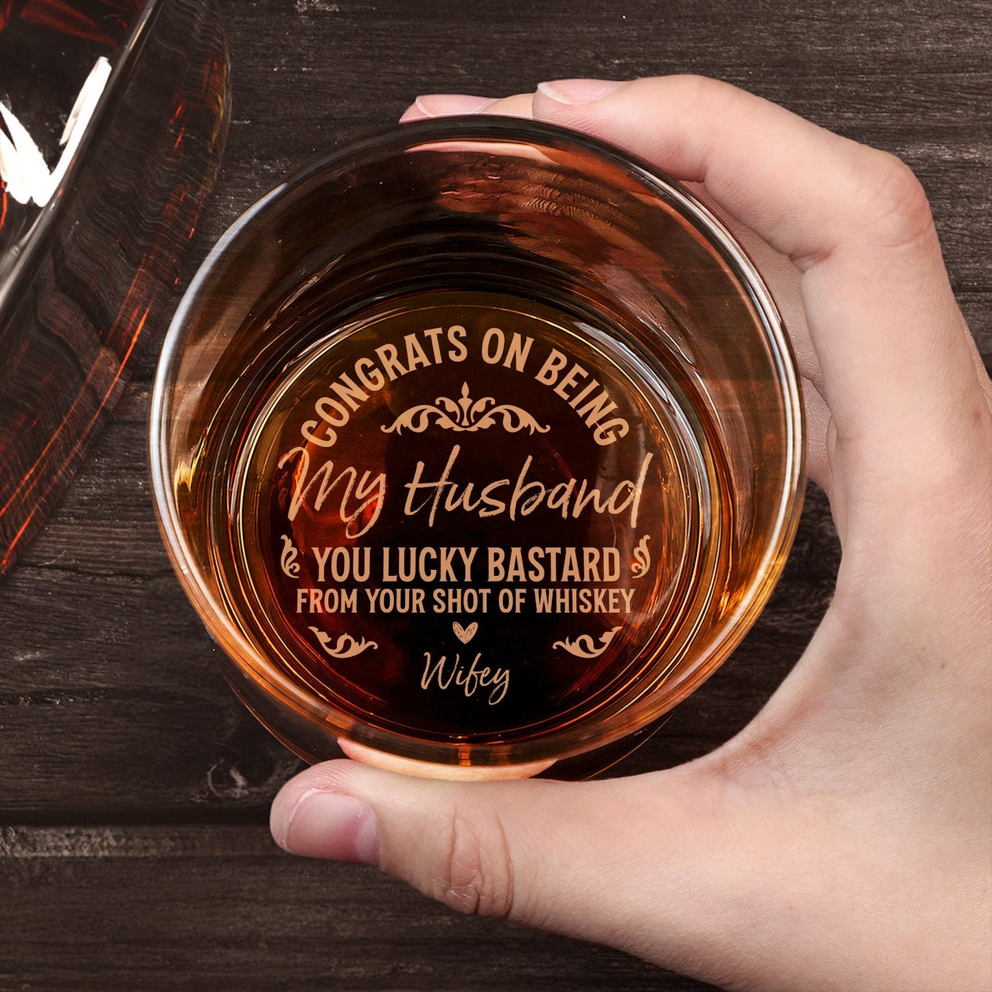 Personalized Whiskey Glass engraved with Congrats on being my husband message held in hand over wood table