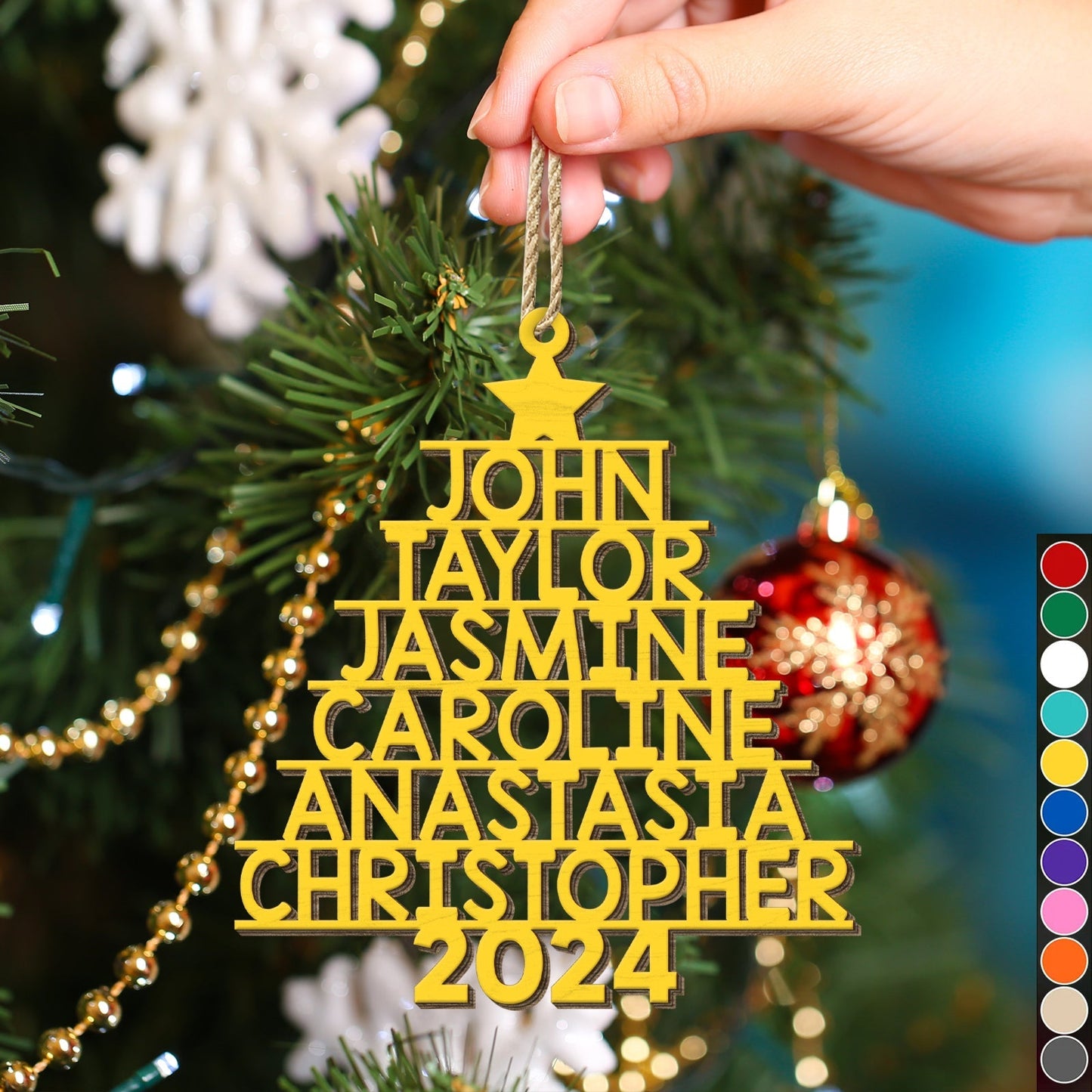 Yellow personalized Christmas tree ornament shaped like a tree with names and 2024 hanging on a Christmas tree