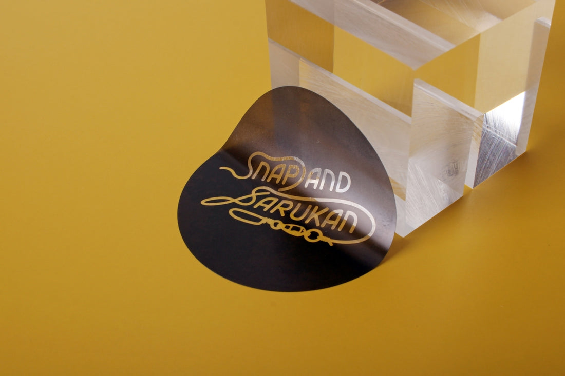 A black sticker with gold text sits near object.