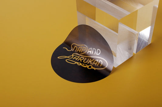 A black sticker with gold text sits near object.