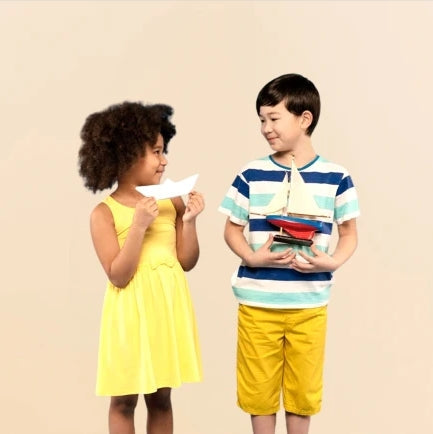 Two children holding paper and toy boats showcasing playful personalized baby gifts and custom keepsakes for kids