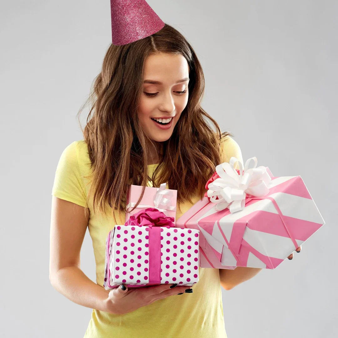 Smiling woman in party hat holding pink wrapped presents representing personalized gifts for her collection
