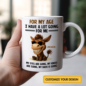 Hand holding white ceramic mug with sunglasses donkey and humorous text for my age I have a lot going for me mug name Jackson