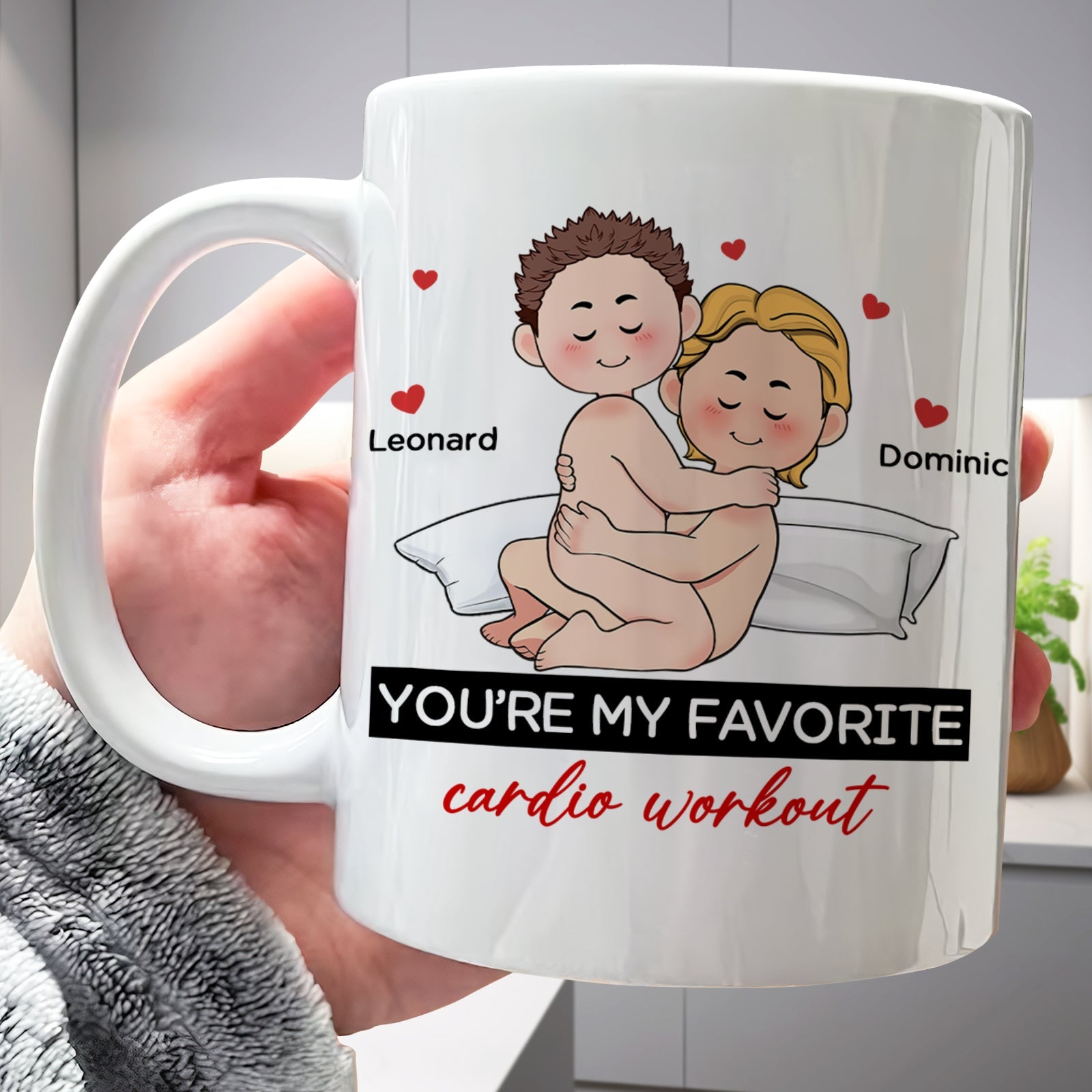 White ceramic personalized couple mug showing cartoon couple cuddling on pillow with names Leonard and Dominic and red hearts
