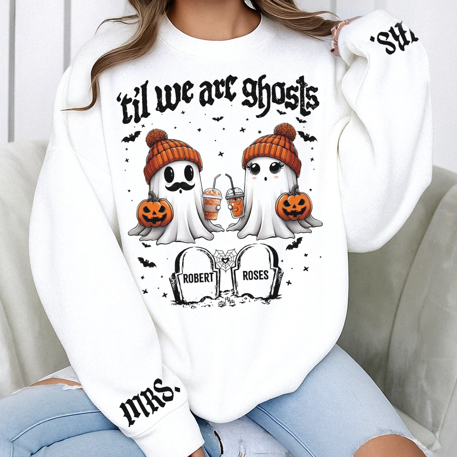 White personalized Halloween couple shirt showing two ghosts in orange beanies holding pumpkins and tombstones with names