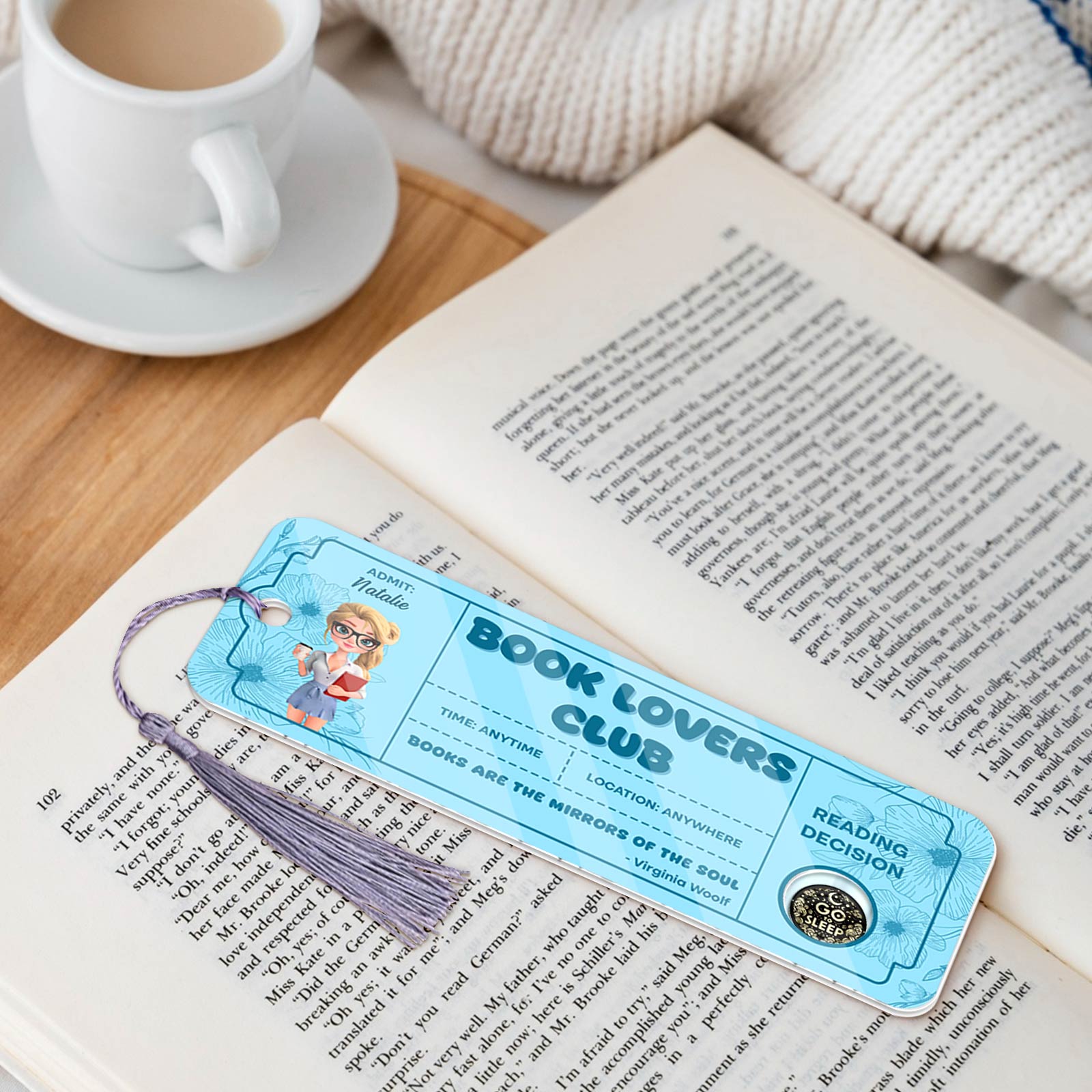 Bookmark For Book Lovers with blue design and tassel placed on an open book beside a cup of coffee