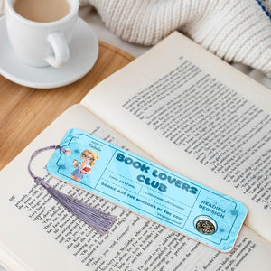 Bookmark For Book Lovers with blue design and tassel placed on an open book beside a cup of coffee