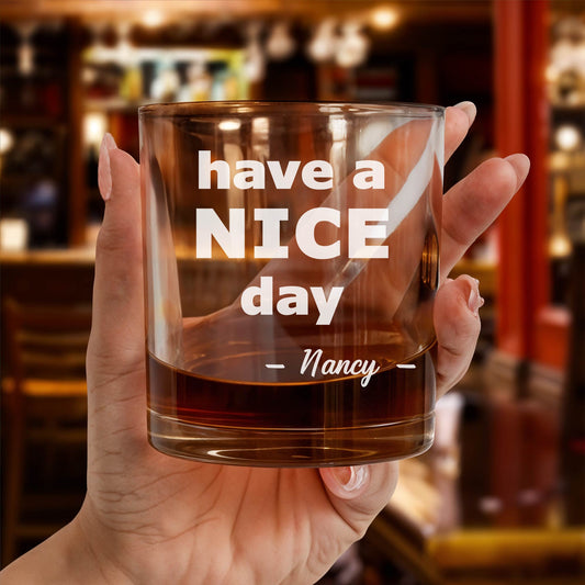 Personalized Whiskey Glass held in hand engraved with have a NICE day Nancy text in bar setting