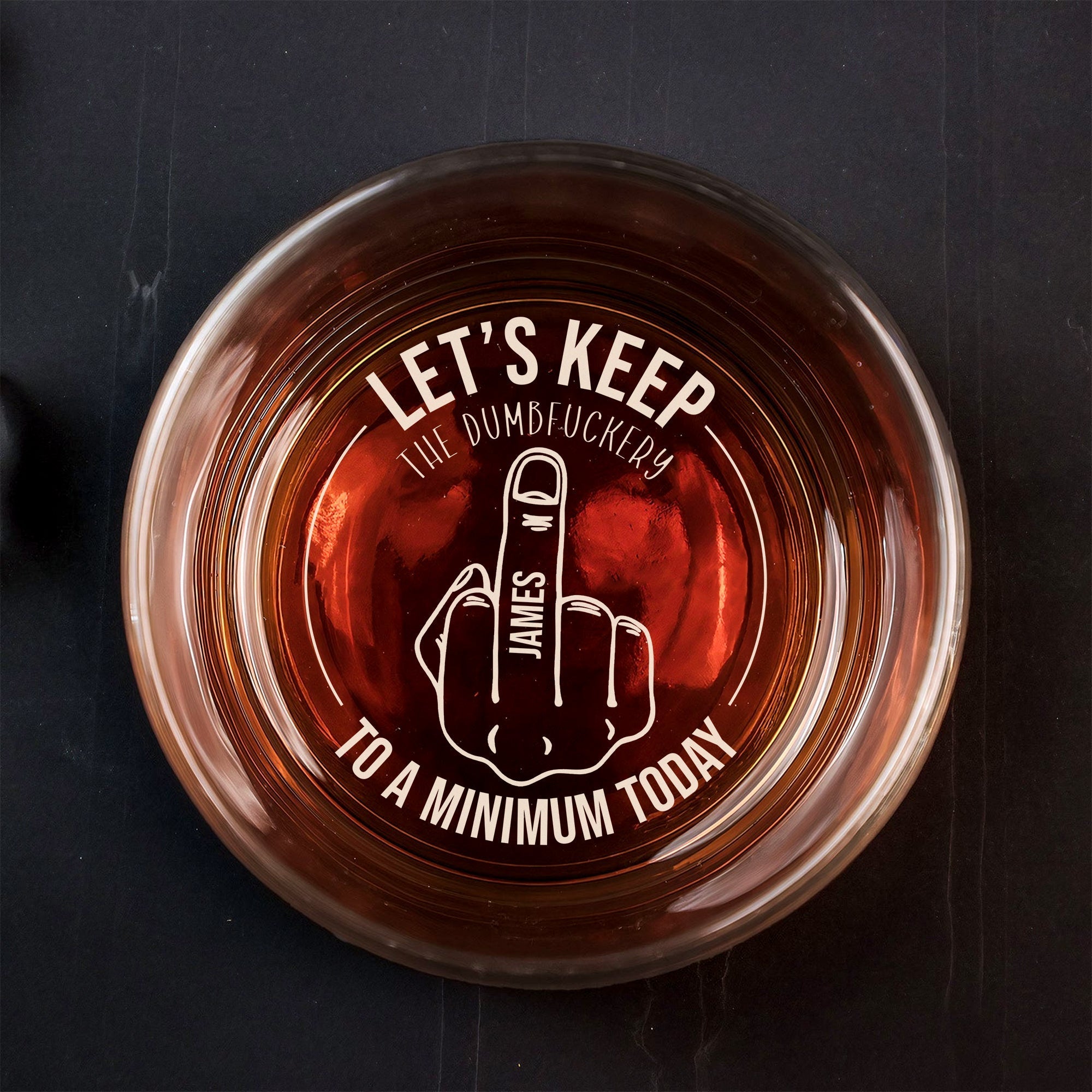Top view Personalized Whiskey Glass filled with amber whiskey and white cheeky middle finger engraving with name James