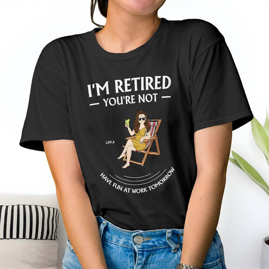 Black personalized retirement t-shirt with I’m Retired You’re Not graphic sitting on chair holding drink