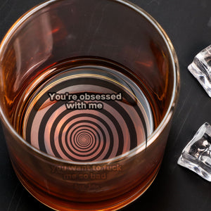 Personalized Whiskey Glass showing amber whiskey with concentric spiral base and cheeky bold message inside
