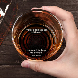 Personalized Whiskey Glass held in hand over wooden table showing concentric target and explicit printed message