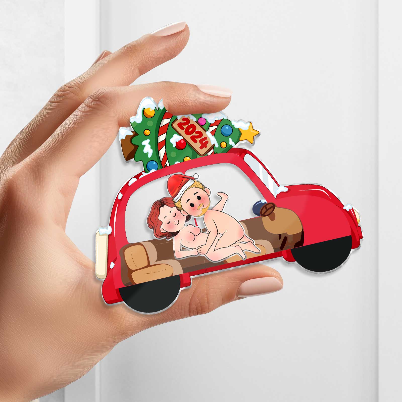 Hand holding a personalized couple keychain shaped like a red car with a Christmas tree and cartoon couple inside