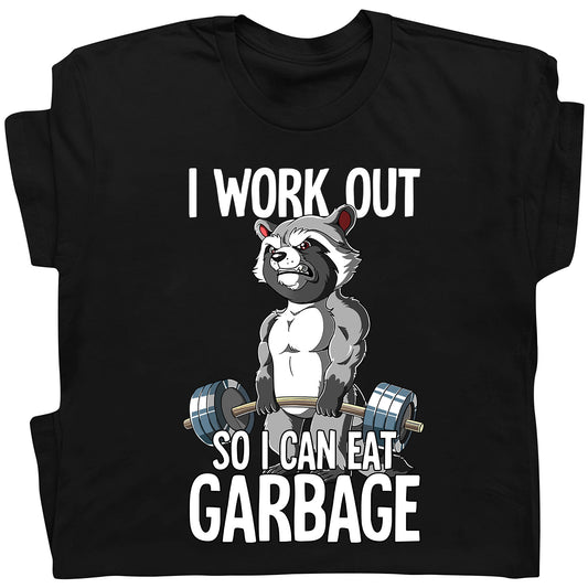 Black t-shirt featuring humorous workout apparel with a muscular raccoon lifting weights and text I work out so I can eat garbage
