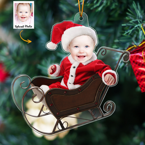 Personalized baby photo ornament featuring a baby in Santa outfit sitting in a sleigh with Christmas tree background