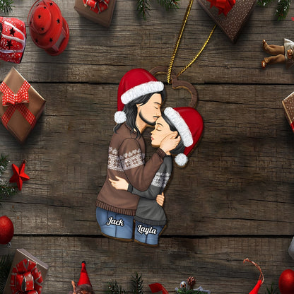 Personalized couple Christmas ornament featuring a kissing couple wearing Santa hats and cozy sweaters with names Jack and Layla