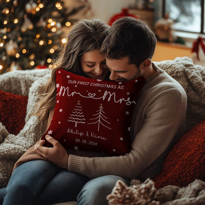 Couple hugging a personalized first Christmas pillow with names and date in a cozy festive living room