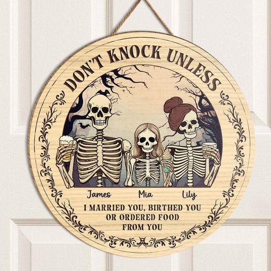 Personalized Halloween wooden door sign featuring skeleton characters with custom names for a spooky welcome