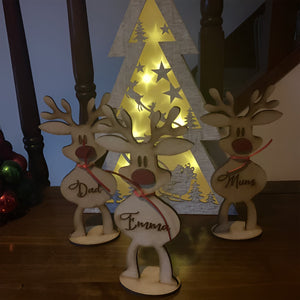 Personalized reindeer family decoration with Dad Emma and Mum names in front of lighted Christmas tree