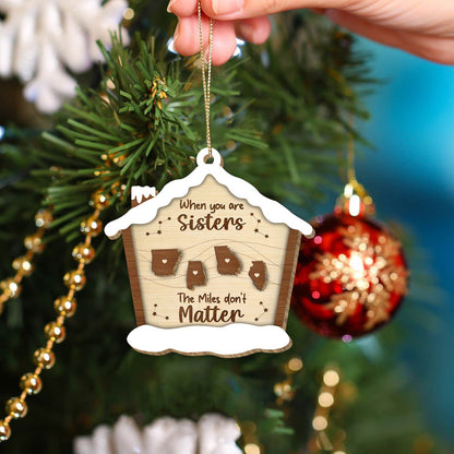 Personalized Christmas ornament with sisters quote and state shapes hanging on tree branch